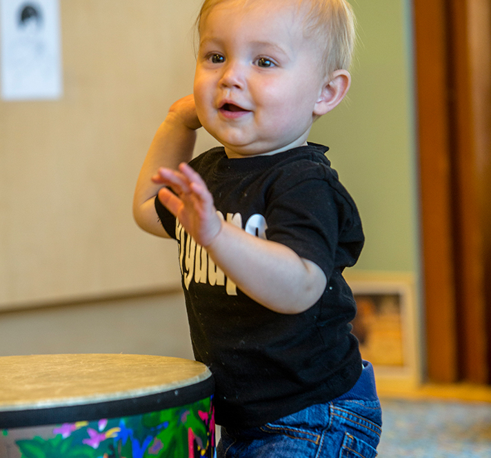 Toddler boy playing with a drum and making music